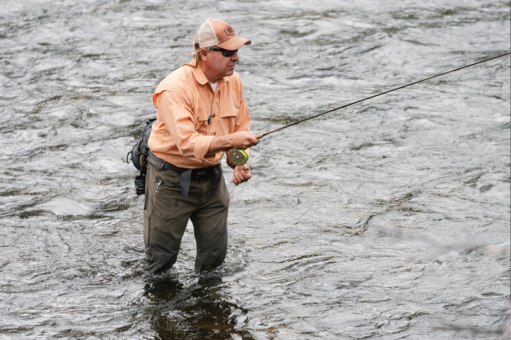 Man standing in river fly fishing