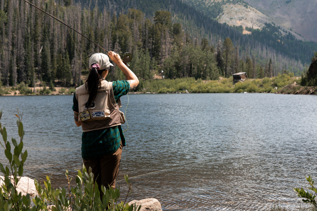 Back of woman casting into alpine lake