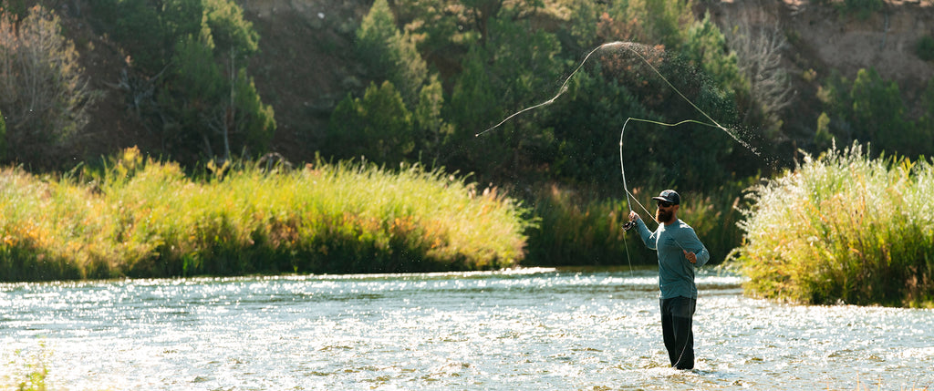 Man casting in the sun with water spraying off the line
