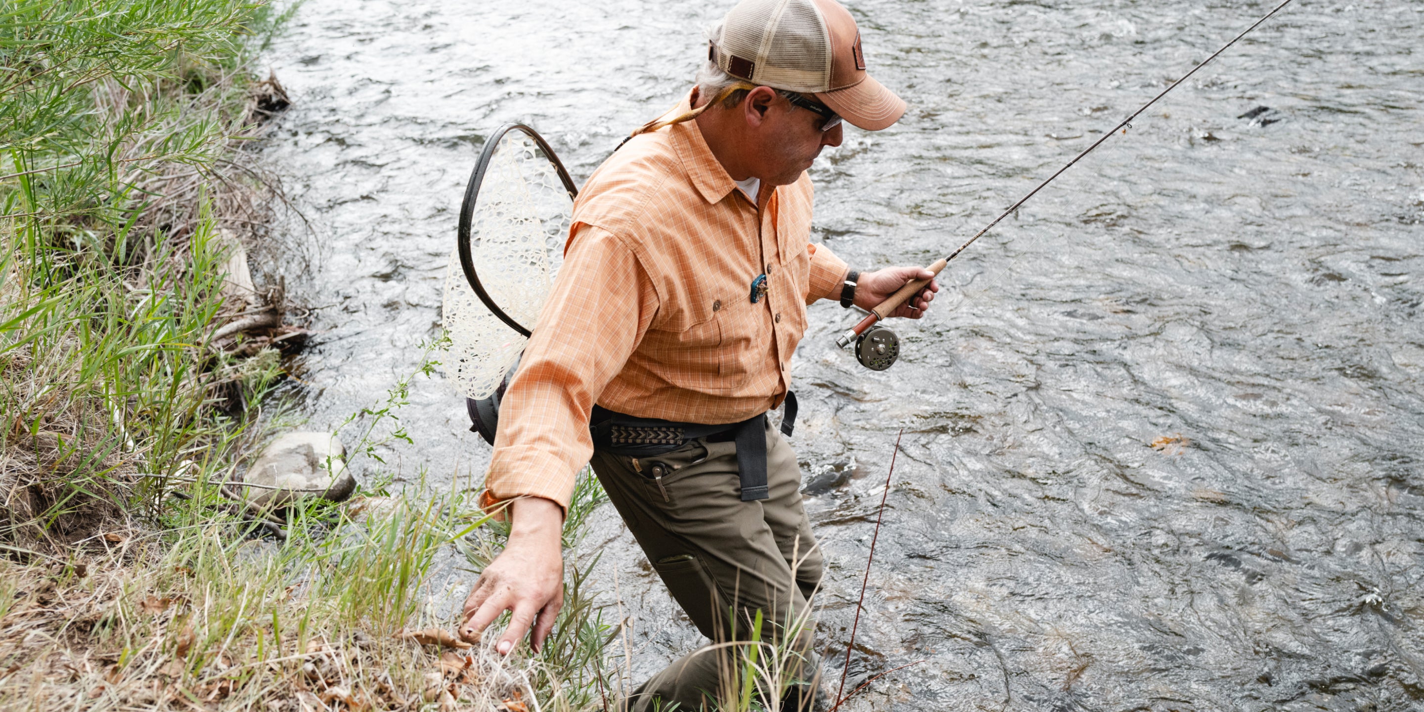 Man stepping into water from small drop holding Classic Trout Kit
